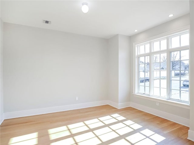 spare room with visible vents, light wood-style flooring, and baseboards