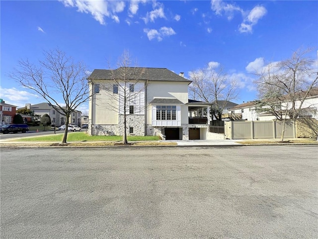 view of front of home with fence, stone siding, and stucco siding