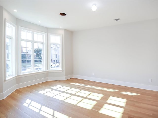 empty room featuring light wood finished floors, visible vents, recessed lighting, and baseboards