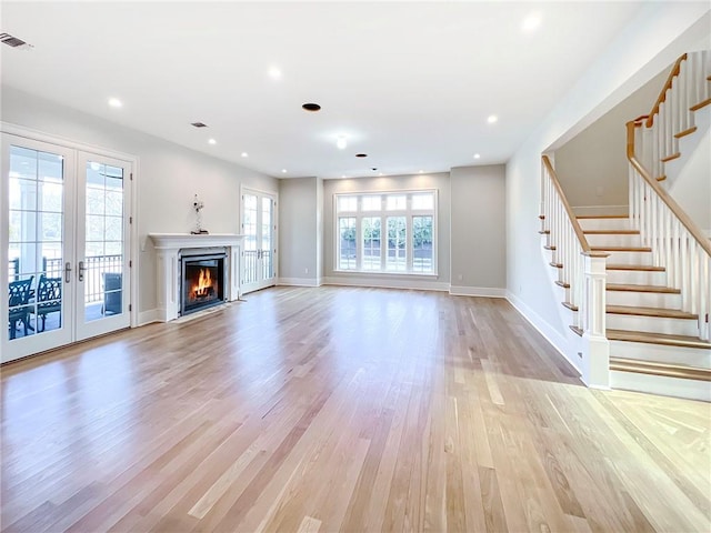 unfurnished living room with light wood-style flooring, recessed lighting, french doors, baseboards, and stairs