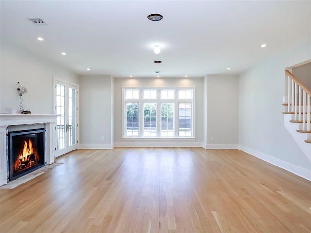 unfurnished living room featuring visible vents, stairway, a fireplace with flush hearth, recessed lighting, and light wood-style floors