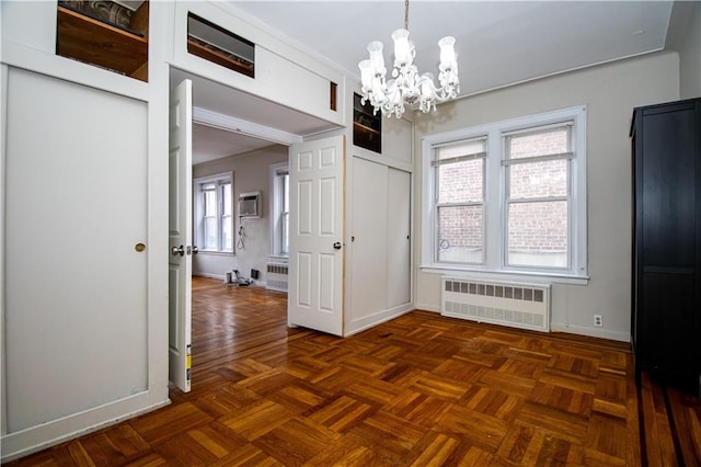 unfurnished dining area featuring baseboards, a chandelier, radiator heating unit, and a wall unit AC