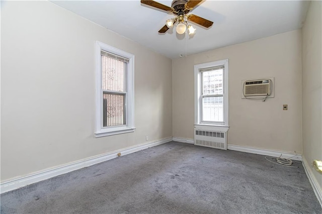 carpeted spare room with radiator heating unit, a ceiling fan, baseboards, and a wall mounted air conditioner