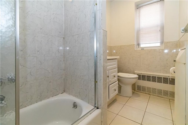 bathroom with radiator, tile patterned flooring, wainscoting, tile walls, and toilet