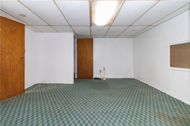 unfurnished room with carpet flooring, baseboards, and a drop ceiling