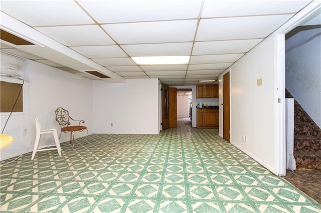 finished basement with a paneled ceiling and light carpet