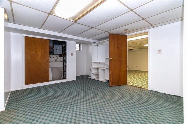 finished basement with electric panel, a drop ceiling, and carpet