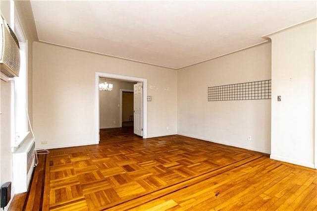 spare room featuring an inviting chandelier, baseboards, and a wall mounted air conditioner