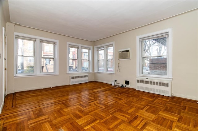 unfurnished room featuring an AC wall unit, radiator heating unit, and baseboards