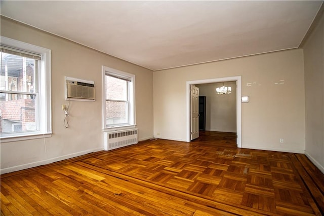 spare room featuring baseboards, a notable chandelier, an AC wall unit, and radiator heating unit