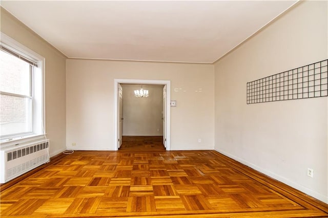 empty room with baseboards, an inviting chandelier, and radiator heating unit