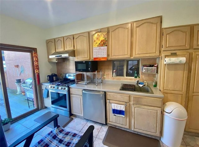 kitchen featuring under cabinet range hood, stainless steel appliances, light countertops, and light brown cabinetry