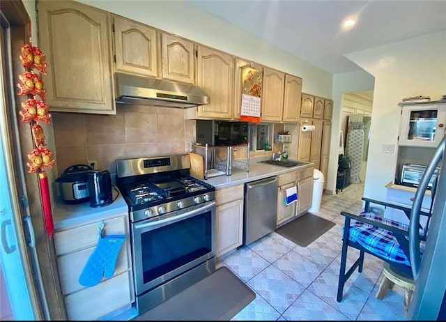 kitchen featuring a sink, tasteful backsplash, ventilation hood, appliances with stainless steel finishes, and light countertops