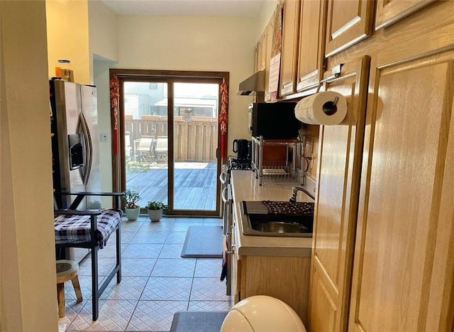 kitchen with brown cabinetry, light tile patterned floors, stainless steel fridge with ice dispenser, and a sink