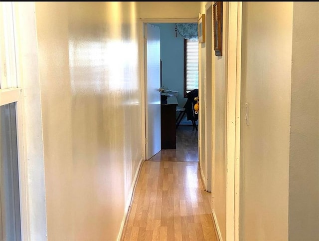 hallway featuring baseboards and light wood finished floors