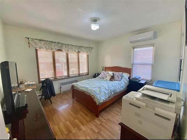 bedroom with light wood-type flooring, multiple windows, radiator, and an AC wall unit