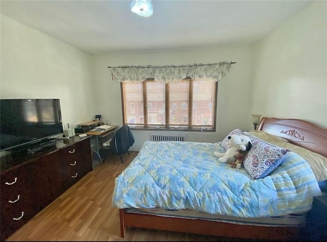 bedroom with radiator and wood finished floors