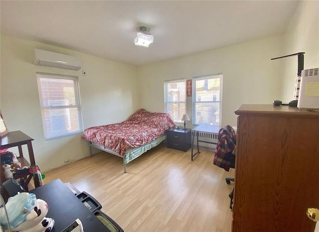 bedroom with radiator, light wood-style floors, and a wall unit AC