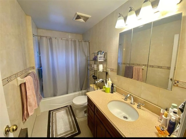 bathroom featuring visible vents, shower / tub combo with curtain, toilet, tile walls, and vanity