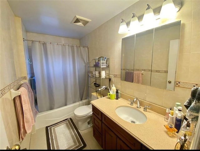 bathroom featuring visible vents, toilet, vanity, shower / bath combination with curtain, and tile walls