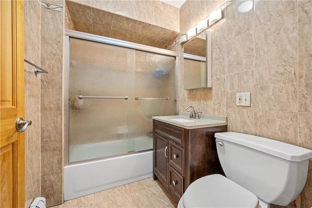 full bathroom featuring enclosed tub / shower combo, toilet, tile walls, and vanity