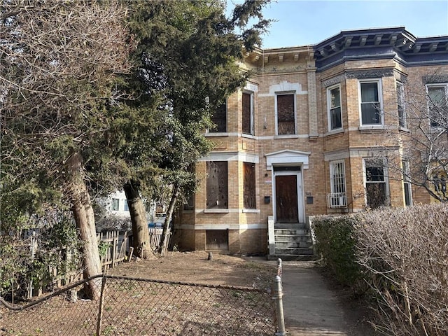 view of front facade featuring entry steps, fence, and brick siding