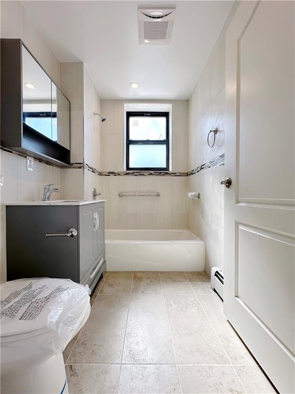 1307 84th St Unit 3C, Brooklyn, NY 11228 - full bath with vanity, a baseboard radiator, toilet, washtub / shower combination, and tile patterned flooring