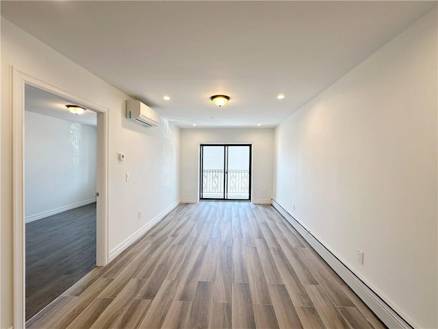 spare room featuring recessed lighting, baseboard heating, an AC wall unit, and wood finished floors