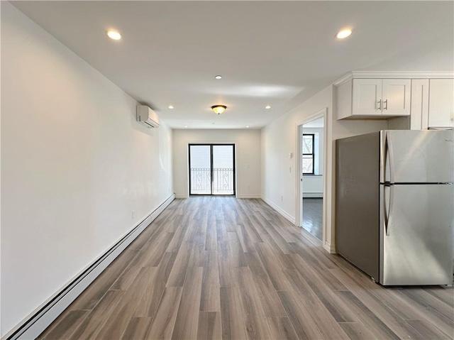 kitchen featuring a baseboard heating unit, recessed lighting, freestanding refrigerator, wood finished floors, and white cabinetry