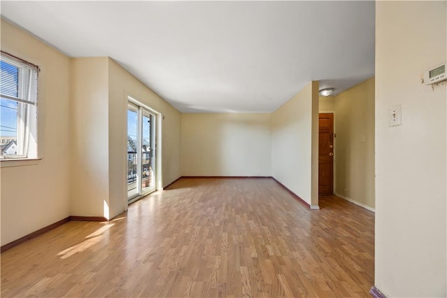 spare room with baseboards and light wood-style floors