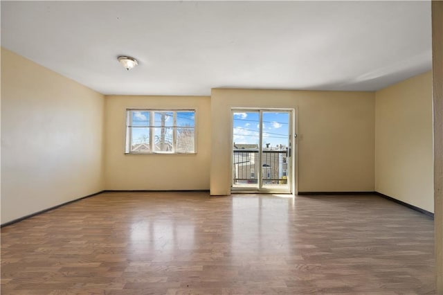 spare room with baseboards and wood finished floors