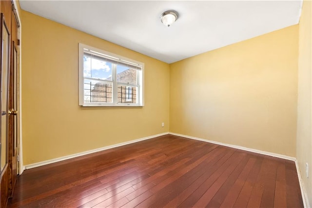 spare room with dark wood finished floors and baseboards