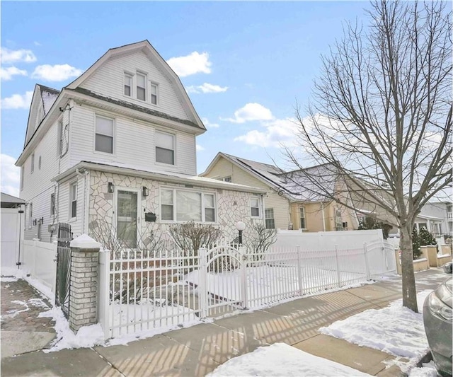 view of front of house with a fenced front yard, a gambrel roof, and a gate