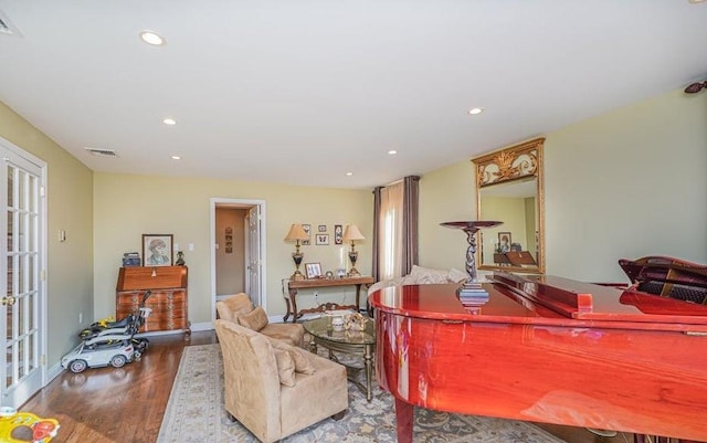 living room with recessed lighting, visible vents, baseboards, and wood finished floors