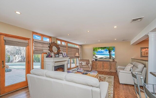 living area featuring light wood-style flooring, recessed lighting, visible vents, and a lit fireplace