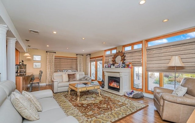 living area featuring recessed lighting, visible vents, a glass covered fireplace, and wood finished floors