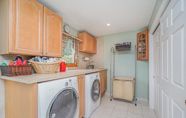 clothes washing area with washing machine and clothes dryer, baseboards, light tile patterned flooring, cabinet space, and a sink