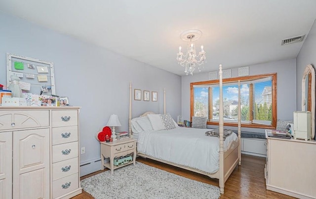 bedroom featuring a baseboard heating unit, an inviting chandelier, wood finished floors, and visible vents