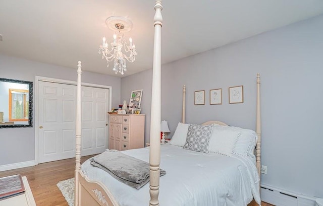 bedroom with a chandelier, light wood-style flooring, baseboards, and a baseboard radiator