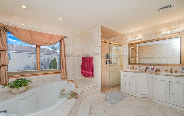 full bath with visible vents, a garden tub, a sink, tile walls, and a shower stall