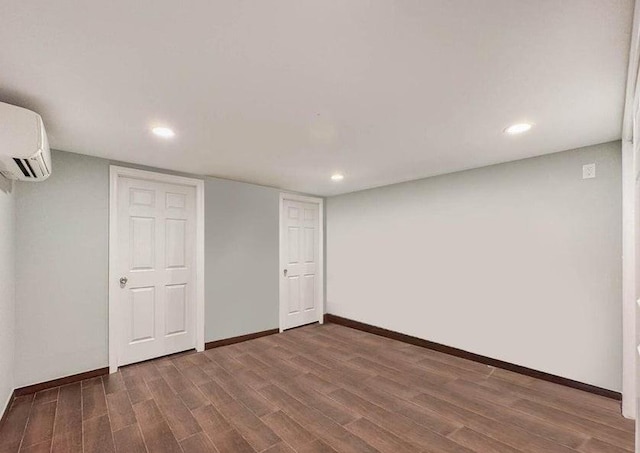 finished below grade area with recessed lighting, baseboards, an AC wall unit, and dark wood-style flooring