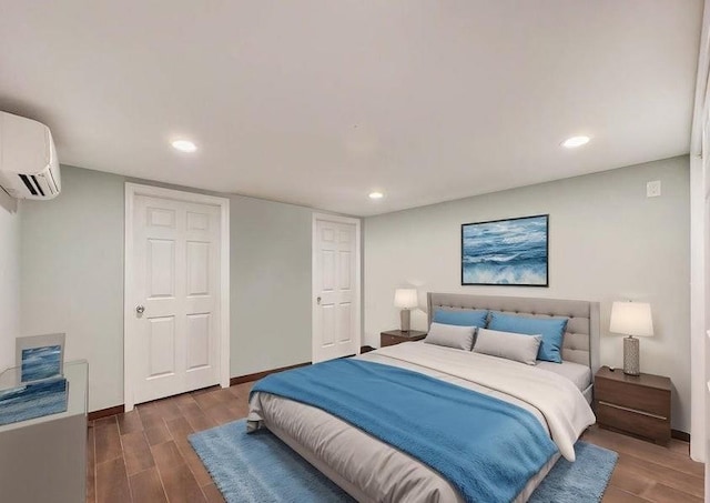 bedroom with recessed lighting, baseboards, wood finished floors, and a wall mounted AC