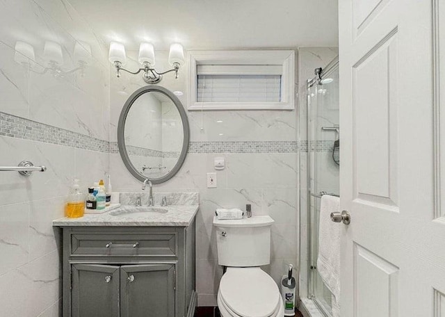 full bath with vanity, a shower stall, toilet, and tile walls