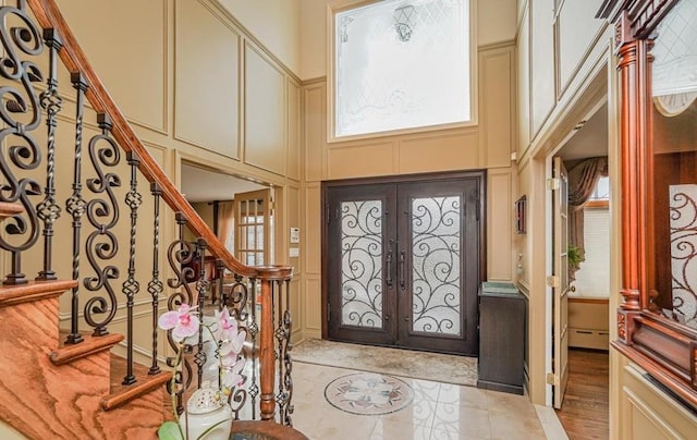 entryway featuring a decorative wall, french doors, and a towering ceiling