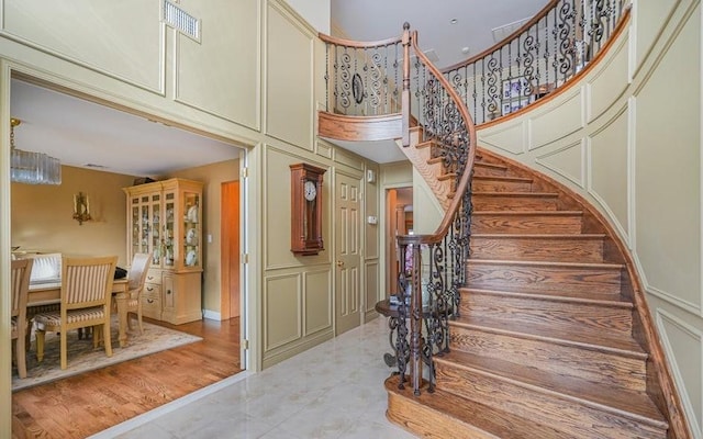 stairs with a high ceiling, a decorative wall, and visible vents