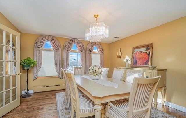 dining area featuring visible vents, baseboards, baseboard heating, wood finished floors, and a notable chandelier