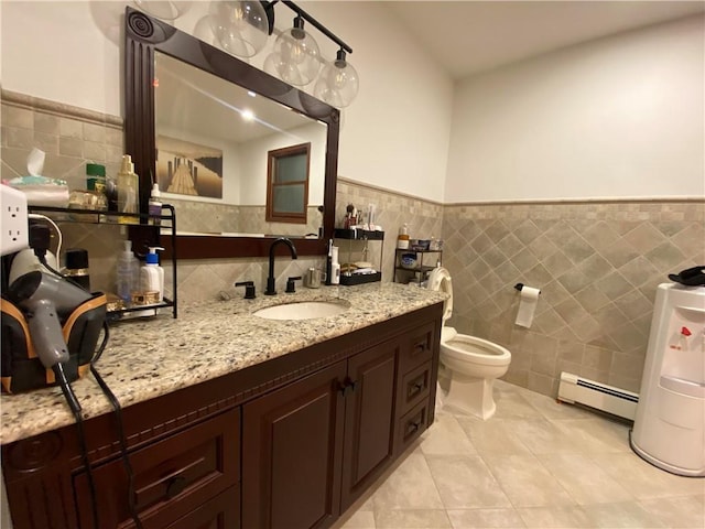 bathroom featuring vanity, baseboard heating, wainscoting, tile patterned floors, and tile walls