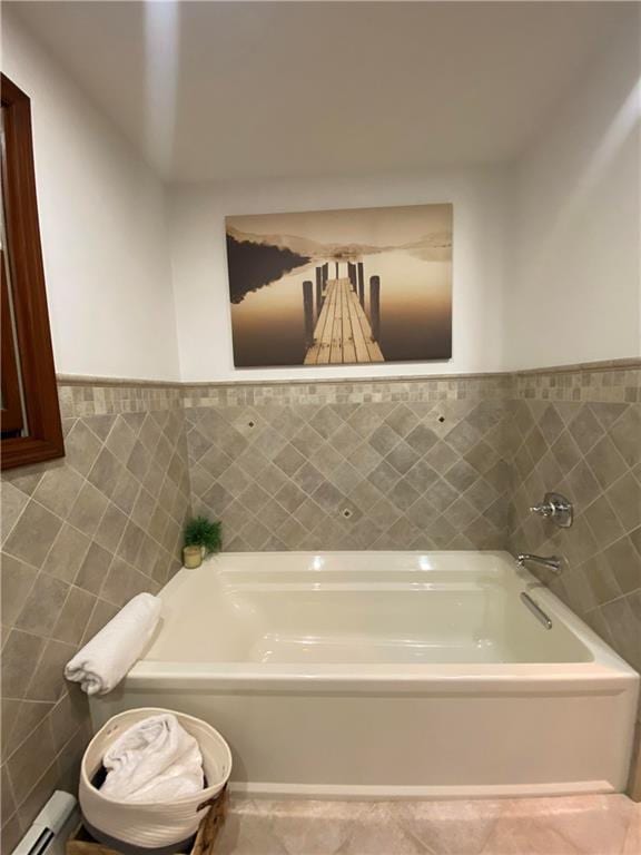 bathroom with a baseboard heating unit, a wainscoted wall, a garden tub, tile patterned floors, and tile walls