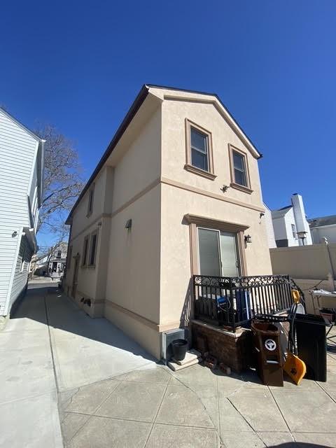 view of side of property featuring stucco siding, fence, and a patio area