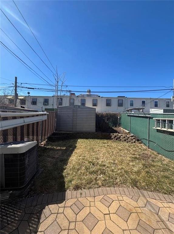 view of yard with an outbuilding, fence, and central AC